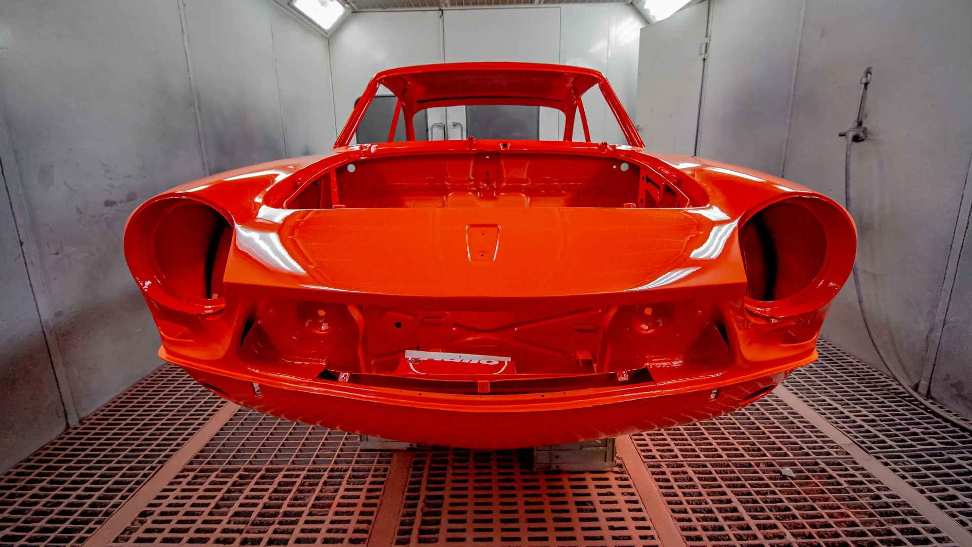 Carrocería de coche pintada de naranja en cabina de pintura
